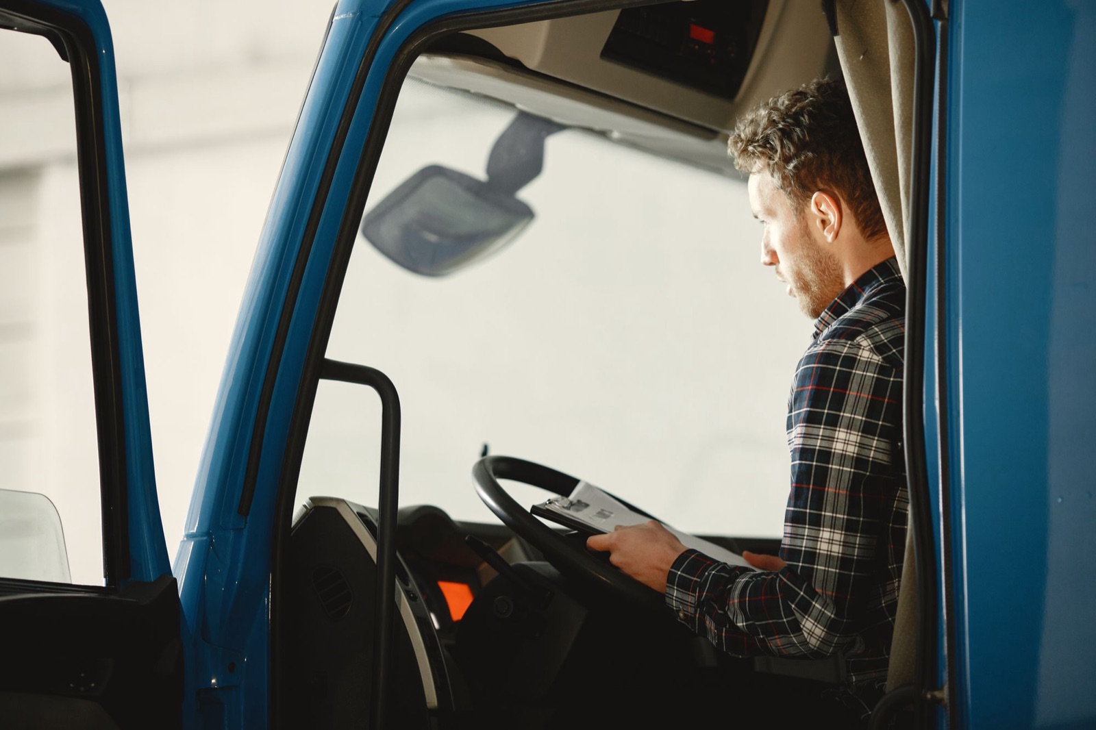 Vrachtwagenchauffeur controleert zijn vrachtpapieren in de cabine