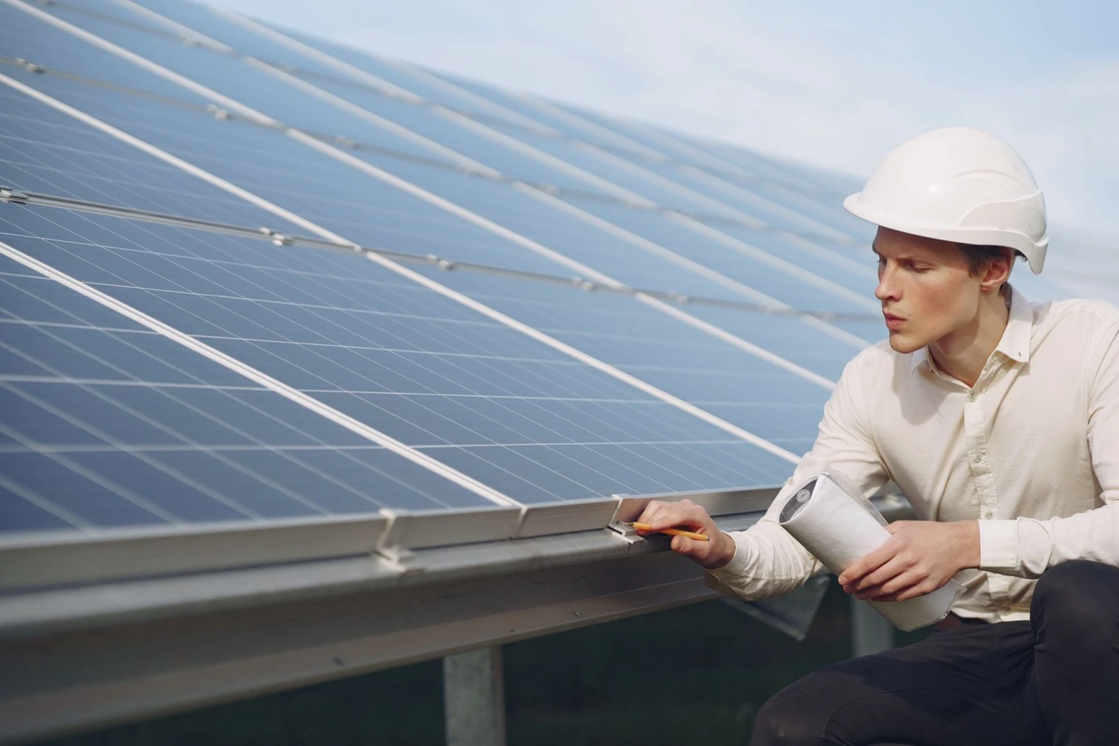 Technicus met helm inspecteert een rij zonnepanelen
