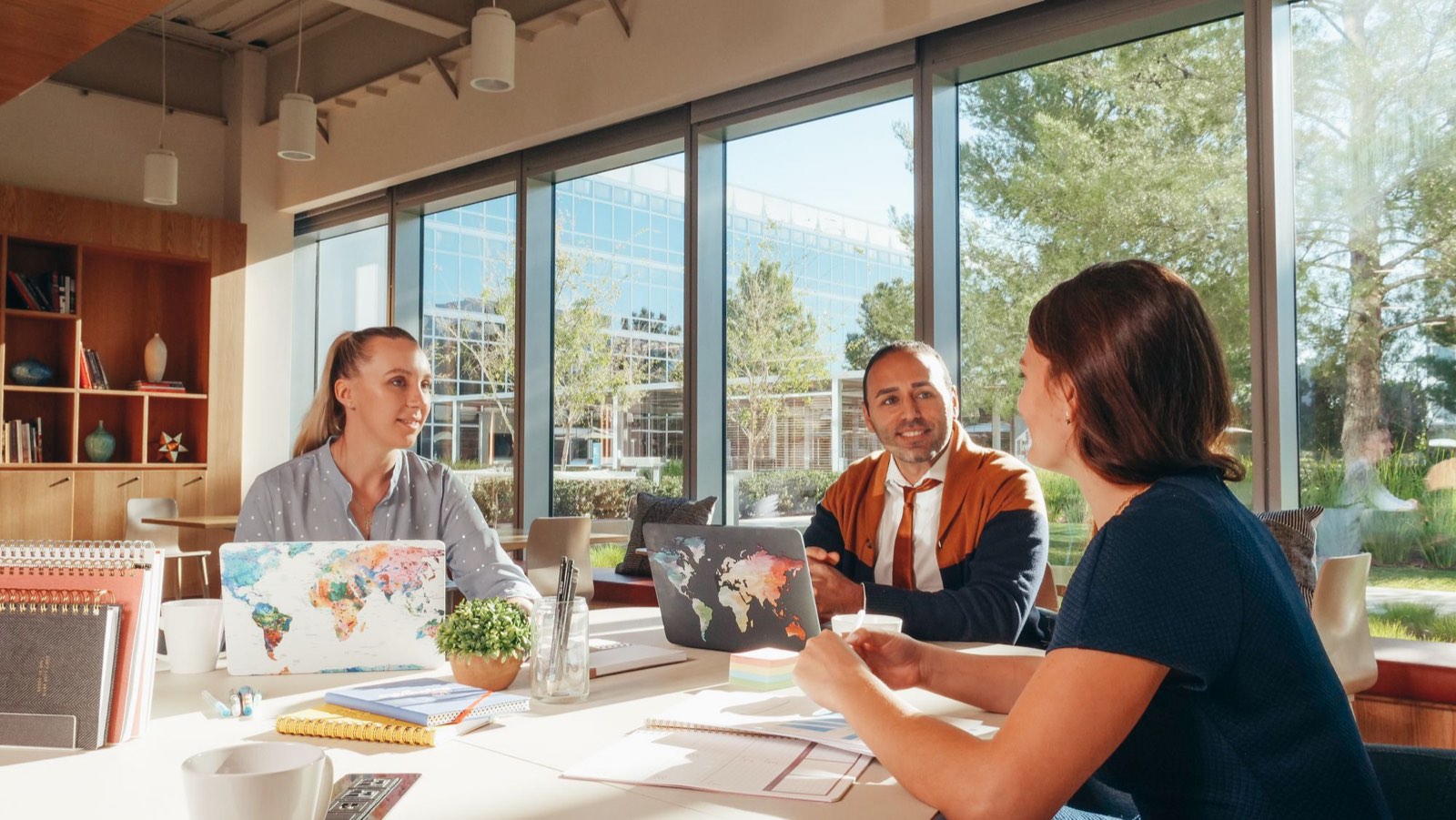 Drie collega’s in overleg aan een tafel bij het raam