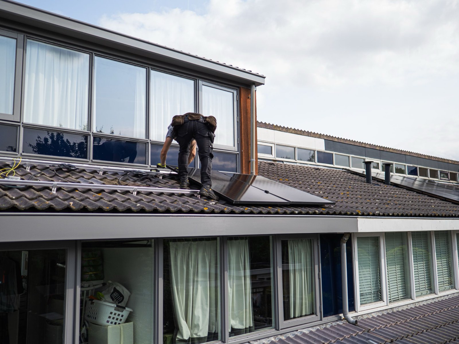 Installateur legt zonnepanelen op het dak van een rijtjeshuis